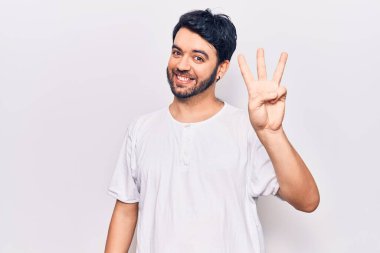 Gündelik kıyafetler giyen genç İspanyol adam üç numarayı gösterip işaret ederken kendinden emin ve mutlu gülümsüyor.. 