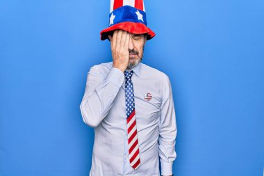 Orta yaşlı, yakışıklı, vatansever, şapkalı ve kravatlı bir adam mavi arka planda. Hatayla el ele tutuşurken şaşırmış. Hatayı unutma. Unuttum, kötü hafıza konsepti.