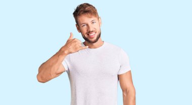 Beyaz günlük tişört giyen genç beyaz bir adam telefonla el ve parmak hareketleriyle gülümsüyor telefonda konuşur gibi. iletişim kavramları. 