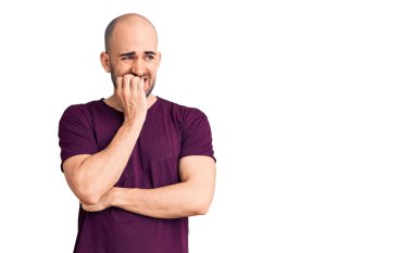 Gündelik tişört giyen genç yakışıklı adam gergin ve gergin görünüyor. Ağzı tırnak yiyen eller. anksiyete. 