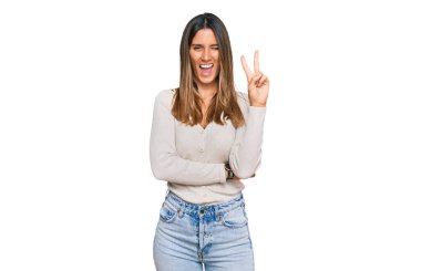 Gündelik kıyafetler giyen, gülümseyen ve kameraya göz kırpan genç bir kadın zafer işareti yapıyor. İki numara.. 