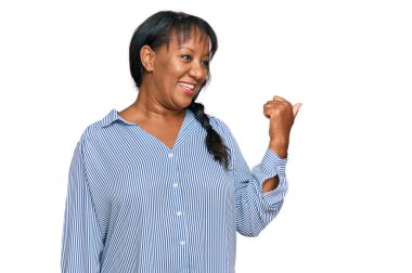 İspanyol, orta yaşlı, sıradan kıyafetler giyen mutlu yüzlü, gülümseyen ve baş parmağıyla yan tarafı gösteren bir kadın.. 