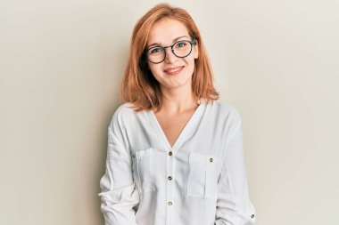 Yüzünde mutlu ve havalı bir gülümseme olan günlük kıyafetler ve gözlük takan beyaz bir kadın. şanslı kişi. 