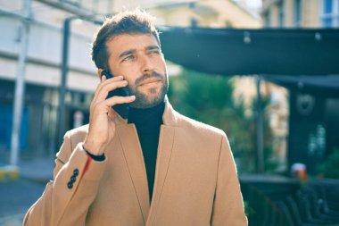 Zarif ceketli yakışıklı bir iş adamı. Açık havada akıllı telefon kullanıyor.