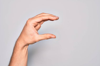 İzole edilmiş beyaz arka plan üzerinde parmaklarını gösteren beyaz bir adamın eli. Görünmez bir şeyi alıp, parmaklarıyla uzayı gösteren bir nesneyi tutuyor.