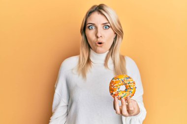 Genç, beyaz bir kadın elinde donut tutuyordu. Korkmuş ve ağzı açık bir şekilde şaşırmıştı. 