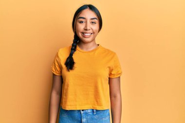 Yüzünde mutlu ve havalı bir gülümseme olan gündelik kıyafetler giyen genç Latin kadın. şanslı kişi. 