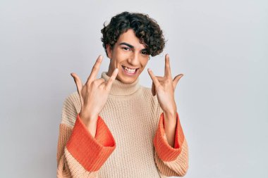 Sıradan bir kazak giyen İspanyol genç adam çılgın bir ifadeyle bağırıyor elleri havada rock sembolü yapıyor. Müzik yıldızı. ağır kavram. 