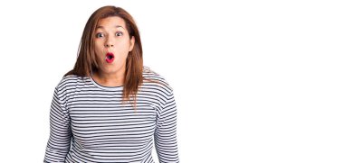 Orta yaşlı, sıradan kıyafetler giyen, ağzı açık, korkmuş, şaşırmış bir Latin kadın. 