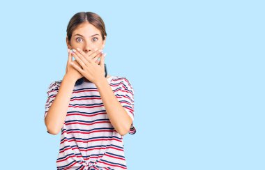 Sarı saçlı, spor kıyafetleri giyen ve kulaklık takan, ağzı yanlışlıkla ellerle kapatan güzel beyaz bir kadın. gizli kavram. 