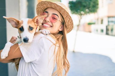 Sarışın, güzel bir kadın dışarıda yavru köpeğe sarılıp sarılıyor.