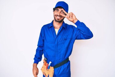 Kıvırcık saçlı ve ayı gibi giyinen yakışıklı genç adam barış sembolü yapıyor. Yüzünde parmaklar, gülümseyerek zaferi gösteriyor. 