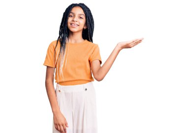 Sevimli Afro-Amerikan kızı günlük kıyafetler giyiyor neşeli bir şekilde gülümsüyor ve avuç içi kameraya bakıyor.. 
