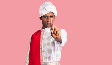 Geleneksel giyinmiş Afrikalı yakışıklı bir adam Sherwani sari giysileri giyiyor. Parmağını kaldırmış ve kızgın bir ifade sergiliyor. 