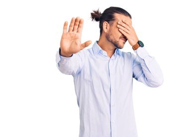 İş kıyafetleri giyen genç yakışıklı adam elleriyle gözlerini kapatıyor ve üzgün ve korku ifadeleriyle jest yapıyor. utangaç ve olumsuz kavram. 