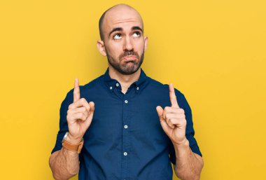 Gündelik kıyafetler giyen genç İspanyol adam üzgün ve üzgün görünüyor, parmaklarıyla yön gösteriyor, mutsuz ve depresif.. 