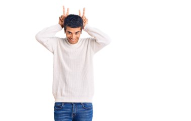 Genç Afrikalı Amerikalı sıradan kıyafetler giymiş komik ve çılgın poz veren parmakları tavşan kulaklı, neşeli gülümseyen 