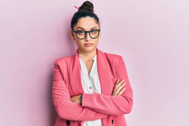 Güzel bir ortadoğulu kadın iş ceketi ve gözlük takıyor şüpheci ve gergin, yüzünde çapraz kollu tasvip etmeyen bir ifade var. negatif kişi. 