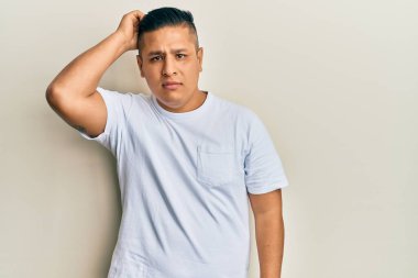 Gündelik beyaz tişört giyen genç latin adam soru sormayı merak ediyor. Şüpheyle kararsız, kafa kafaya düşünerek. Düşünceli kavram. 