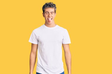 Gündelik beyaz tişört giyen genç yakışıklı adam komik bir ifadeyle dilini dışarı çıkartıyor. duygu kavramı. 