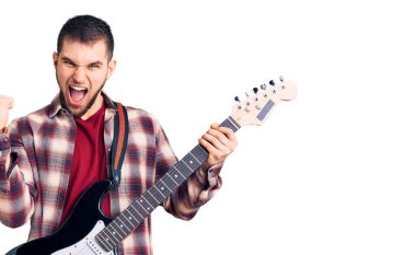 Genç yakışıklı adam elektro gitar çalıyor gururla bağırıyor zaferi kutluyor ve başarıyı kollarını kaldırarak kutluyor. 