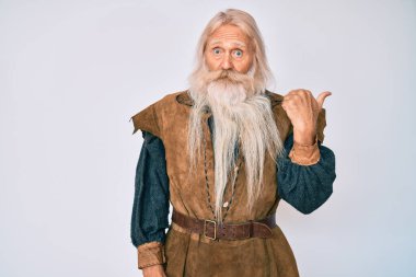 Gri saçlı, uzun sakallı, Viking kostümü giyen yaşlı bir adam elleri yana dönük, ağzı açık ve şaşkın bir şekilde şaşırdı.. 