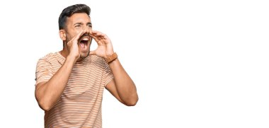 Yakışıklı İspanyol bir adam günlük kıyafetler giyiyor ve elleri ağzında bağırıyor. 