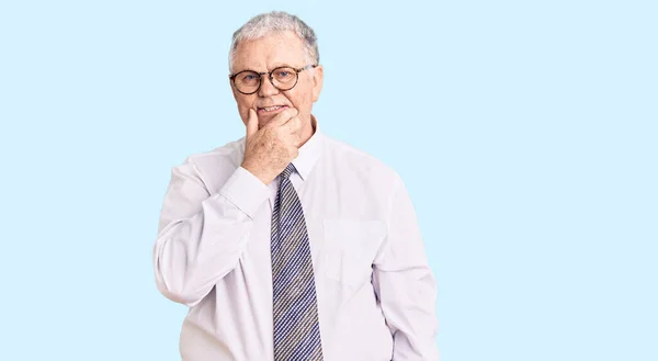 Senior grey-haired man wearing business clothes looking confident at the camera smiling with crossed arms and hand raised on chin. thinking positive.