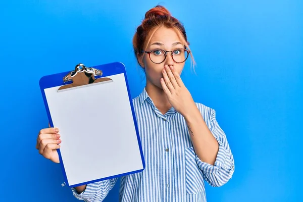 Young Redhead Woman Holding Clipboard Blank Space Covering Mouth Hand — Stock Photo, Image