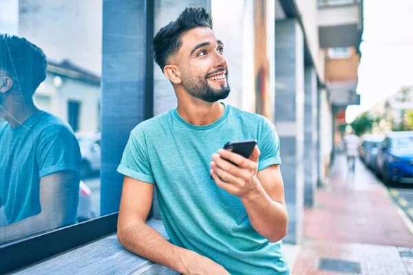 Mladý Arabsky Muž Usměvavý Šťastný Pomocí Smartphone Městě — Stock fotografie