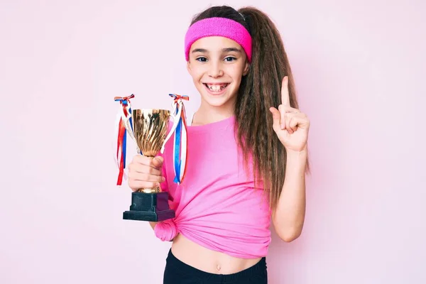 Linda Niña Hispana Usando Ropa Deportiva Sosteniendo Trofeo Ganador Sonriendo —  Fotos de Stock