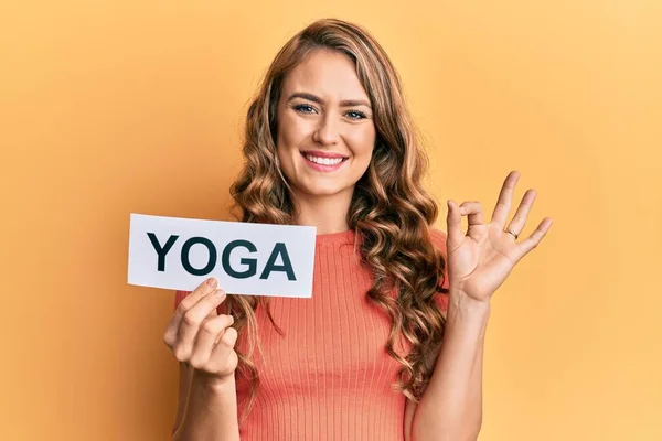 Young Blonde Girl Holding Yoga Message Paper Doing Sign Fingers — Stock Photo, Image