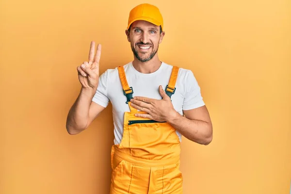 Young Handsome Man Wearing Handyman Uniform Yellow Background Smiling Swearing — Stok fotoğraf