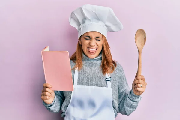 Hispana Joven Chef Mujer Lectura Recetas Libro Palanca Lengua Fuera —  Fotos de Stock