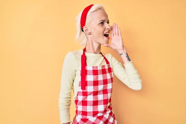 Young Blonde Woman Tattoo Wearing Professional Baker Apron Shouting Screaming — Stock Photo, Image