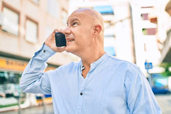 Middle age bald man smiling happy talking on the smartphone at the city.