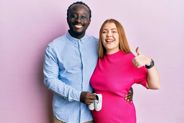 Young Interracial Couple Expecting Baby Holding Shoes Smiling Happy Positive — Stock Photo, Image