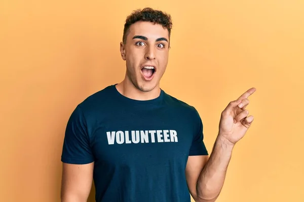 Jovem Hispânico Vestindo Shirt Voluntária Surpreendido Apontando Com Dedo Para — Fotografia de Stock