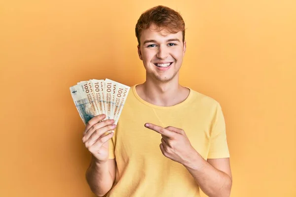 Młody Biały Mężczyzna Trzymając 100 Duński Korona Banknoty Uśmiechając Szczęśliwy — Zdjęcie stockowe
