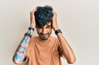 İspanyol asıllı genç adam gündelik giysiler giyiyor. Baş ağrısı çekiyor. Acı ve migren yüzünden çaresiz ve stresli. Eller başının üstünde.. 