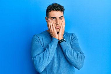 Günlük kazak giyen İspanyol genç adam yorgun eller yüzünü kapatıyor, depresyon ve üzüntü, sorun için üzgün ve rahatsız 