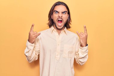 İş kıyafetleri giymiş, çılgın bir ifadeyle bağıran genç yakışıklı adam elleri havada rock sembolü yapıyor. Müzik yıldızı. ağır kavram. 