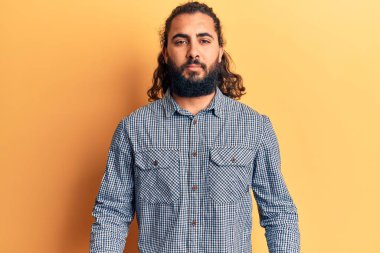 Yüzünde ciddi bir ifade olan gündelik kıyafetler giyen genç bir Arap. Basit ve doğal bir şekilde kameraya bakıyorsun.. 