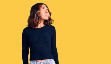 Genç, güzel, melez bir kadın, günlük kıyafetler giyiyor, gülümsüyor, yan tarafa bakıyor ve düşünüyor.. 