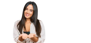 Elleri avuçlarında gülümseyen ya da el hareketi yapan gündelik kıyafetler giyen genç, güzel İspanyol kız. Bekleme ve koruma 