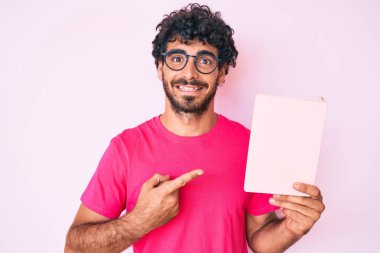 Kıvırcık saçlı ve ayı gibi gülümseyen eli ve parmağı olan yakışıklı genç bir adam. 