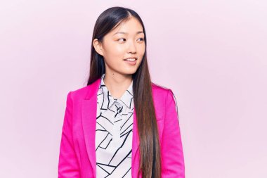 Zarif kıyafetler giyen genç, güzel Çinli bir kadın. Tarafını arıyor, rahat poz veriyor, doğal bir yüzü ve kendine güvenen bir gülümsemesi var.. 