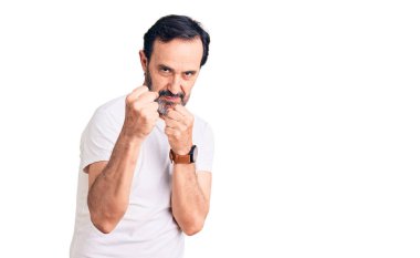 Orta yaşlı yakışıklı bir adam gündelik tişört giyiyor. Yumruk savunma hareketiyle dövüşmeye hazır. Kızgın ve üzgün bir yüz, sorundan korkuyor. 