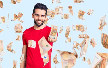 Sakallı, sıradan tişörtler giyen, dostça gülümseyerek selamlaşan genç yakışıklı bir adam. başarılı iş.