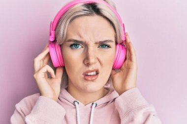 Genç sarışın kız kulaklık takarak müzik dinliyor. şüphe kavramı. 